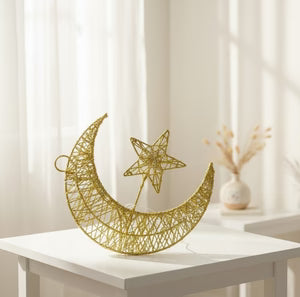Decorative metal wall art with a moon and star design on a white surface.
