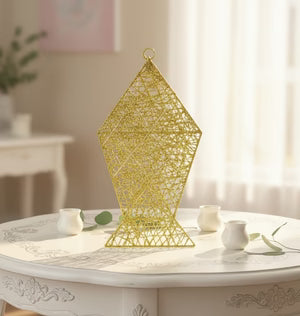 Decorative gold geometric lantern on a white table with a soft, blurred background